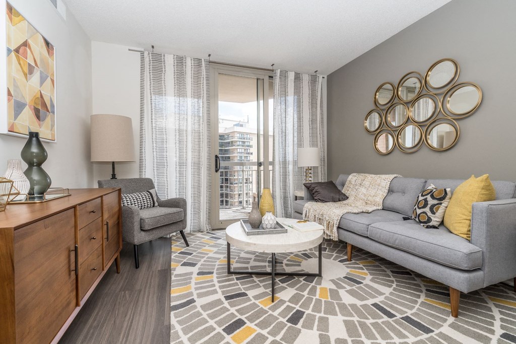 a living room with grey couches and a coffee table   and a window