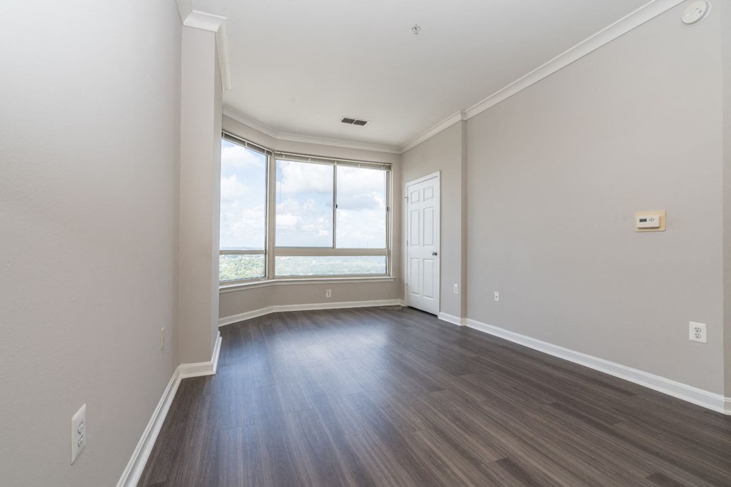 an empty living room with wood floors and a window