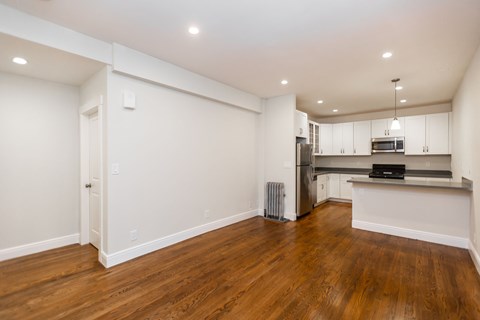 A kitchen with white cabinets and a wooden floor.