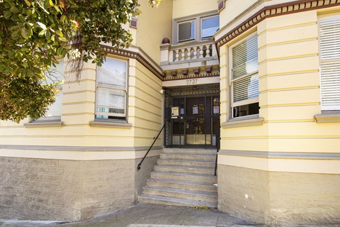 A yellow building with a black door and steps leading up to it.