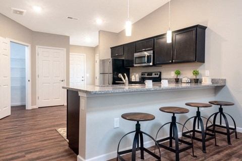 a kitchen with a bar with four stools