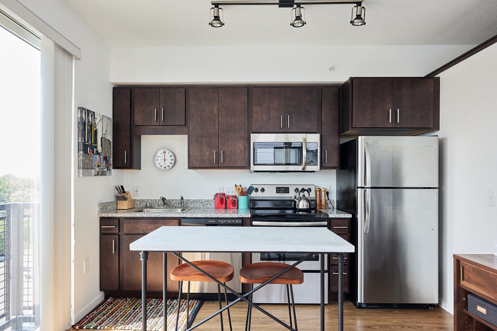 a kitchen with stainless steel appliances and wooden cabinets and a white table with three chairs