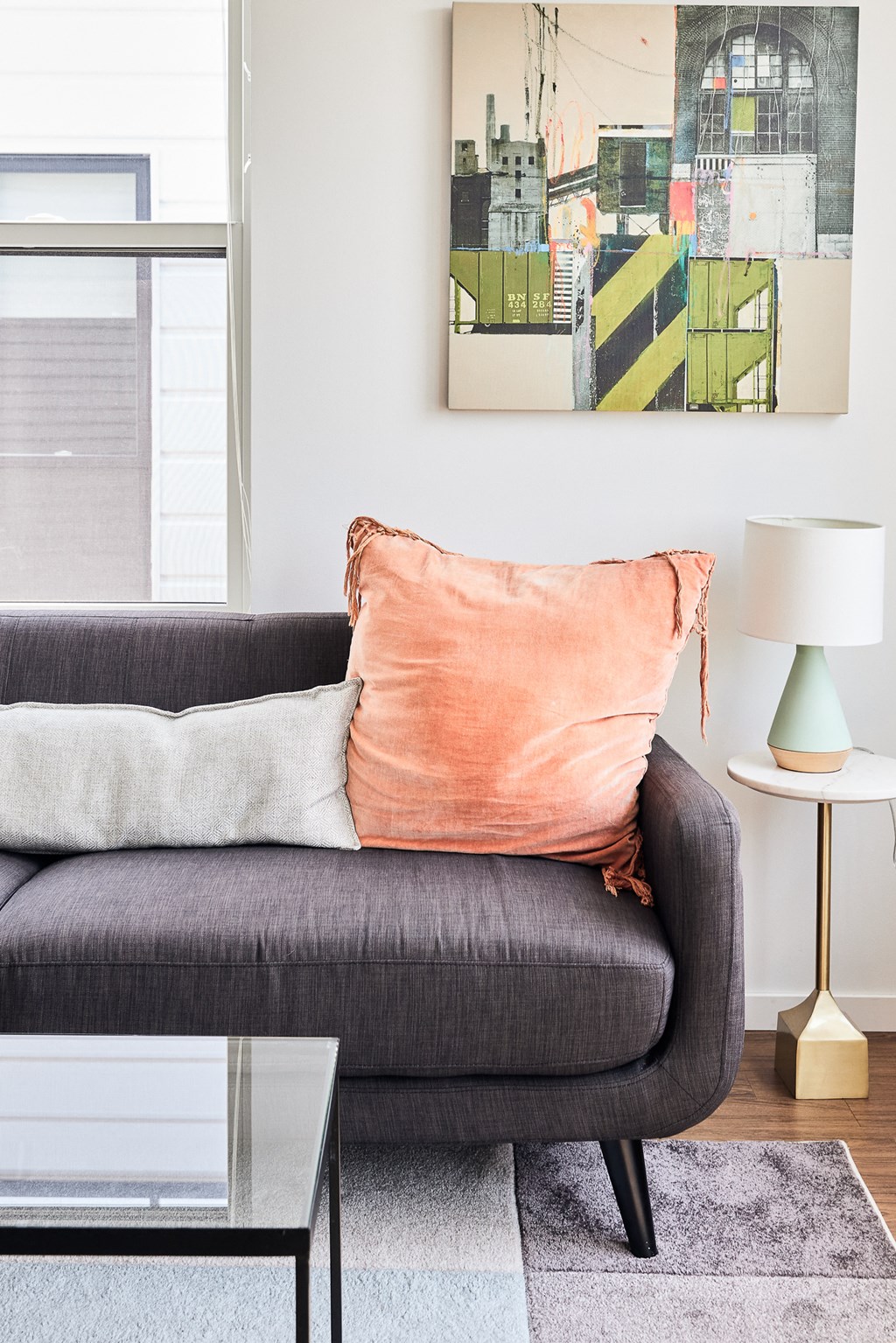 a living room with a gray couch and a peach pillow