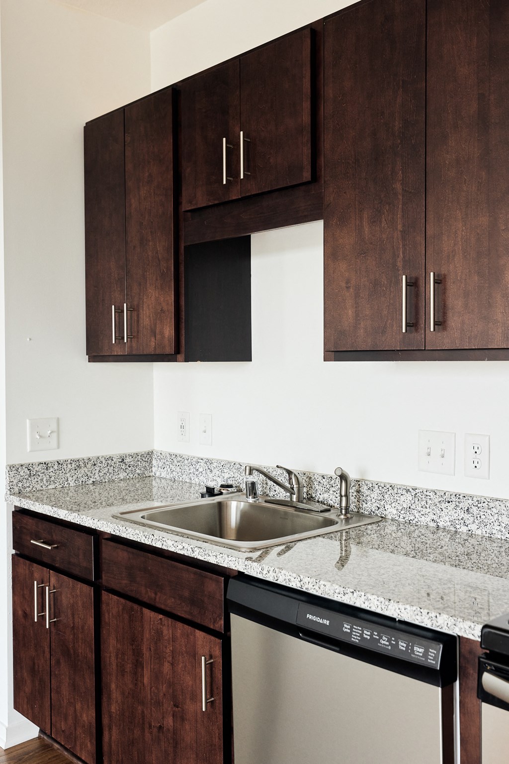 a kitchen with dark wood cabinets and granite counter tops and a dishwasher