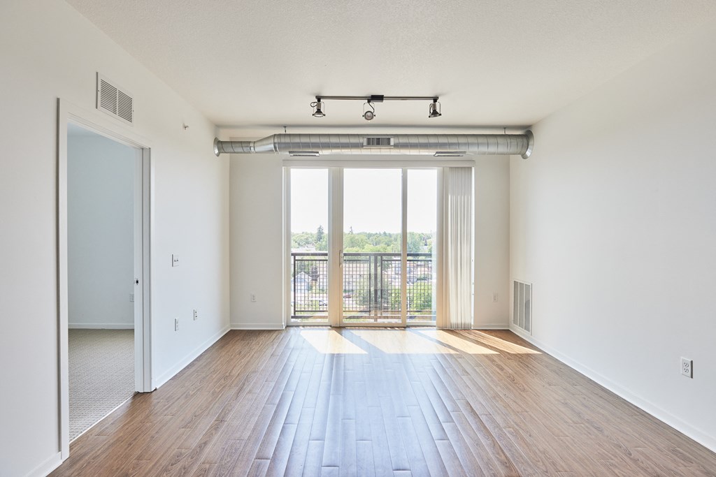 an empty living room with wood floors and a balcony