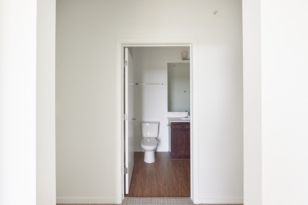 a door open to a bathroom with a toilet and a sink