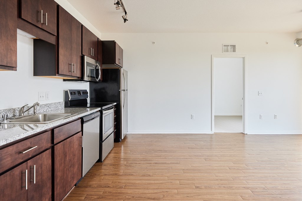 an empty kitchen with wood flooring and black and white appliances