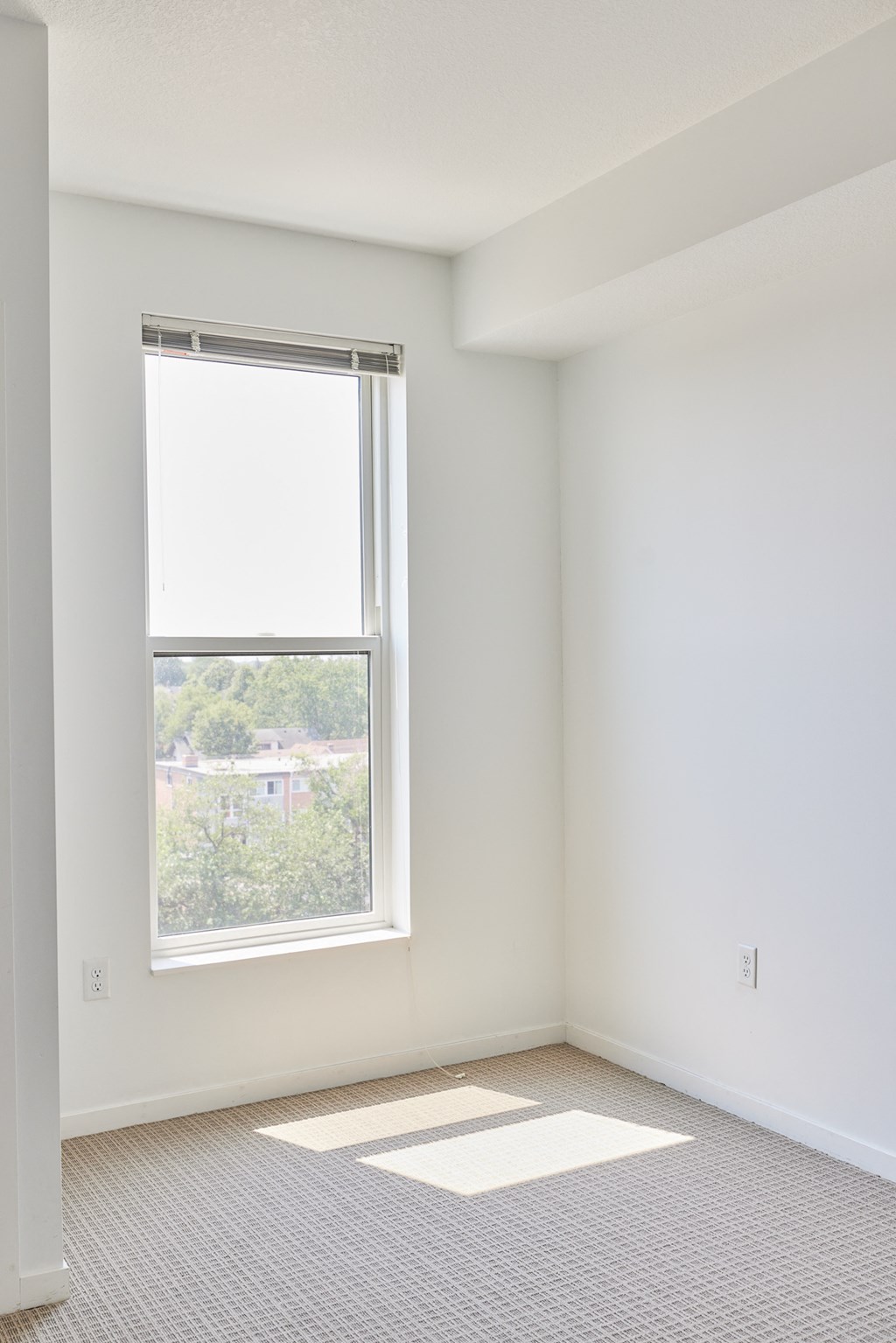 an empty room with a window and white walls