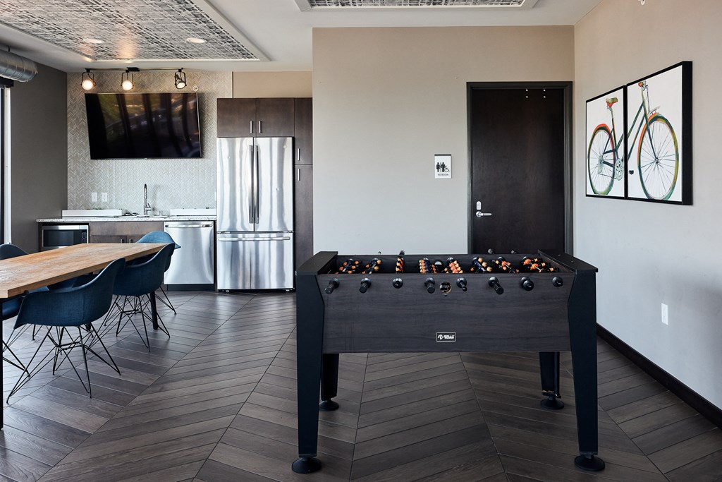 a foosball table in a game room with a kitchen
