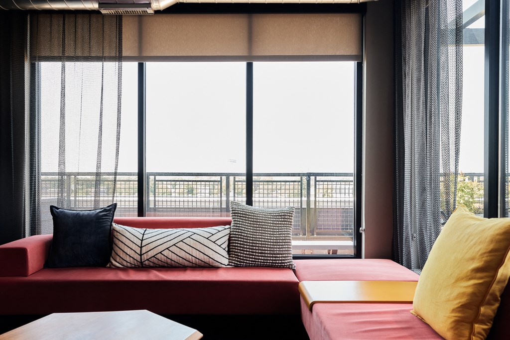 a red couch with pillows in front of a window