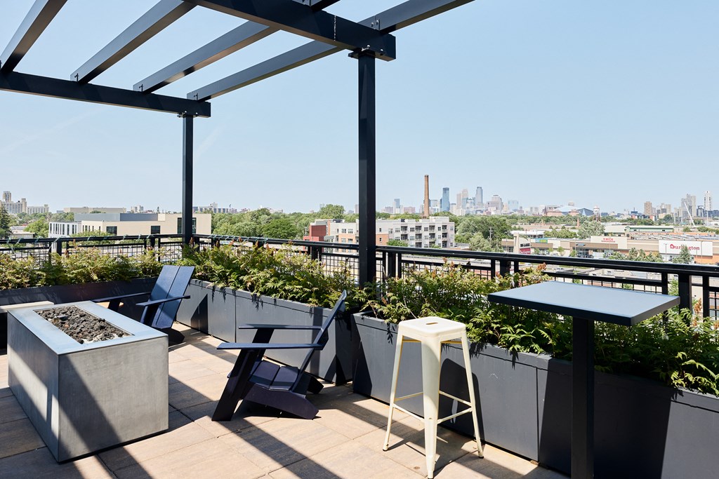 a rooftop patio with tables and chairs and a view of the city