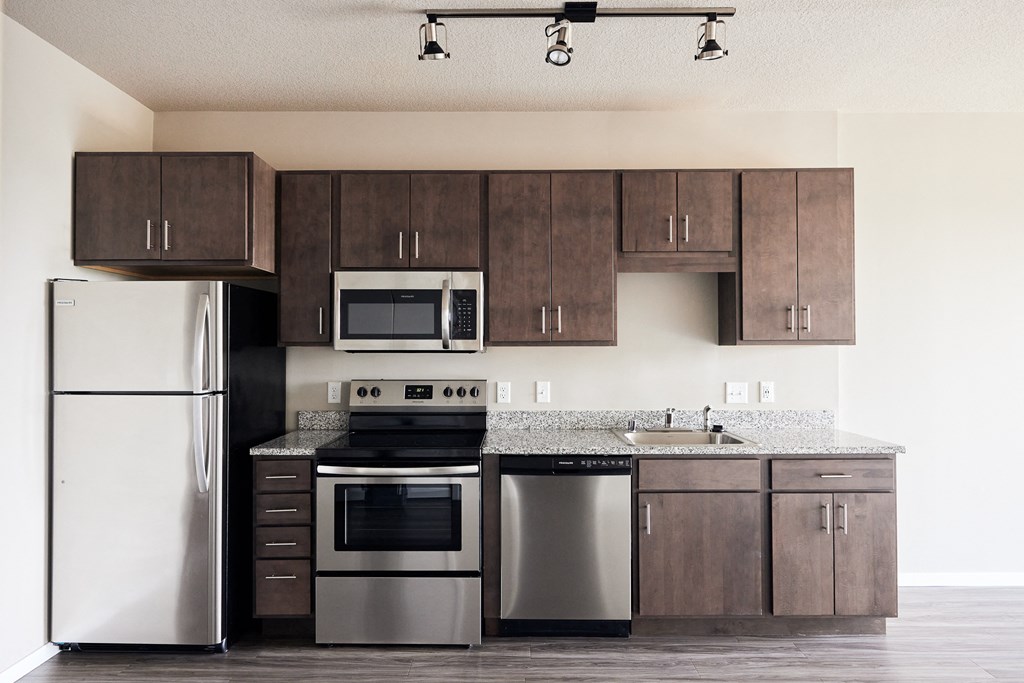 an empty kitchen with stainless steel appliances and wooden cabinets