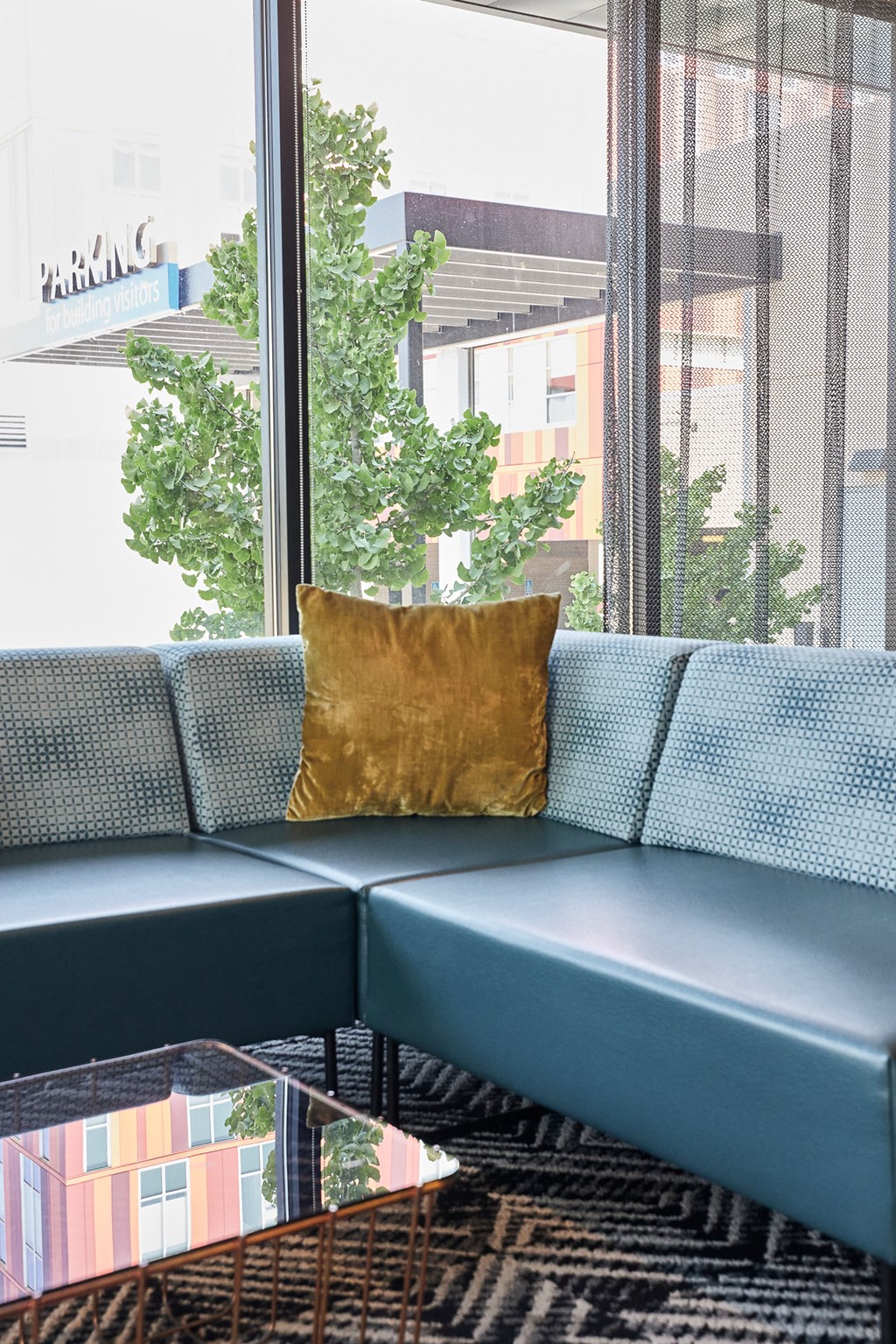 a blue couch with a gold pillow in front of a window
