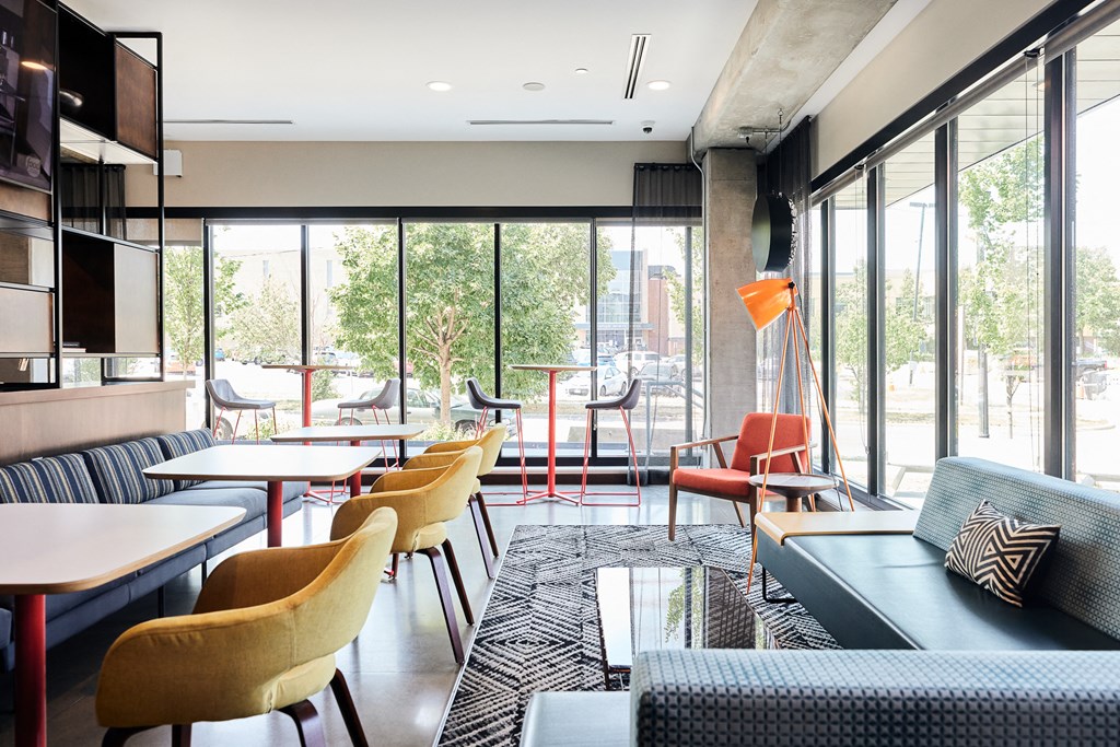 a lounge area with couches tables and chairs and large windows
