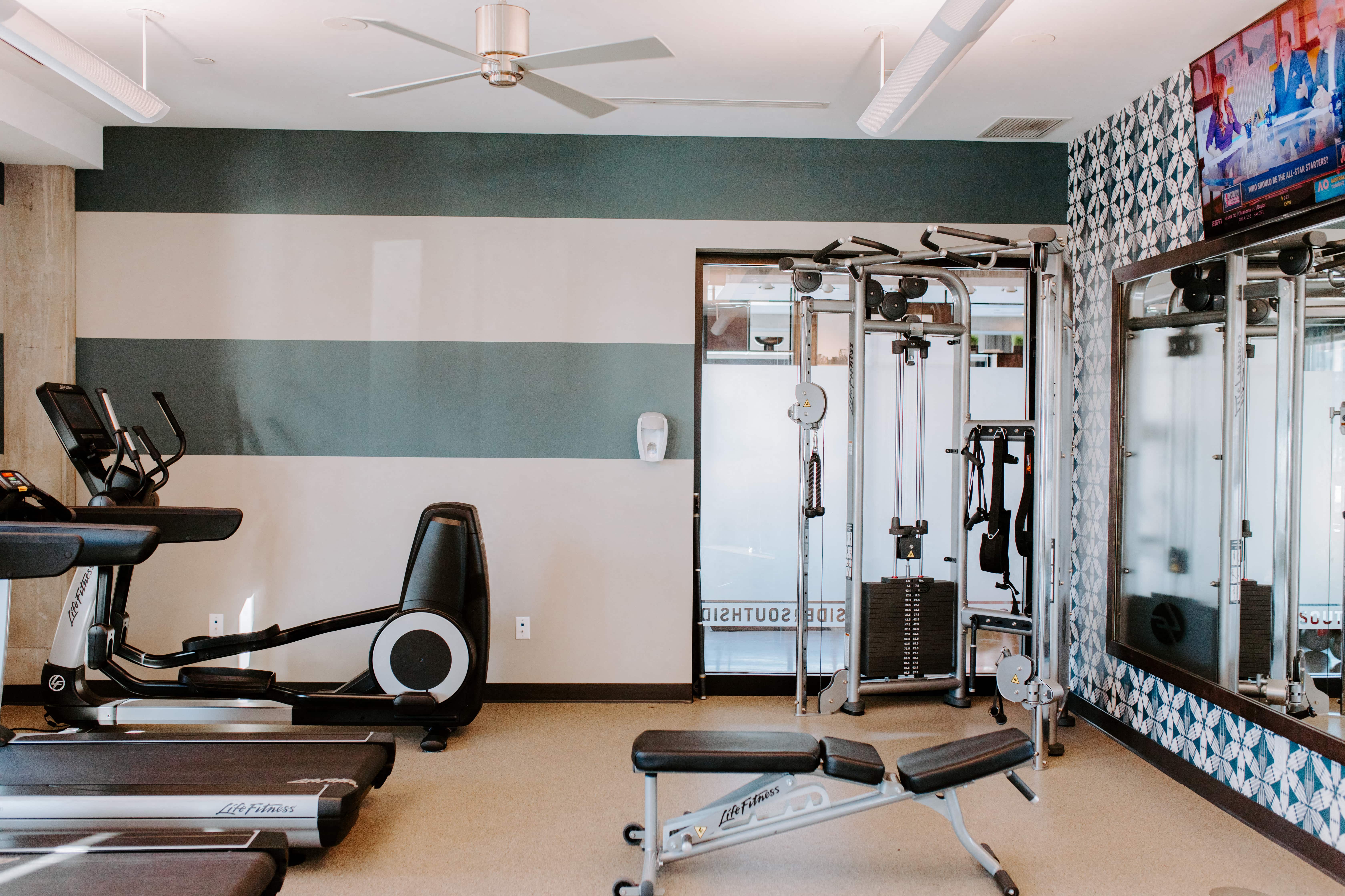 a gym with exercise equipment and a tv
