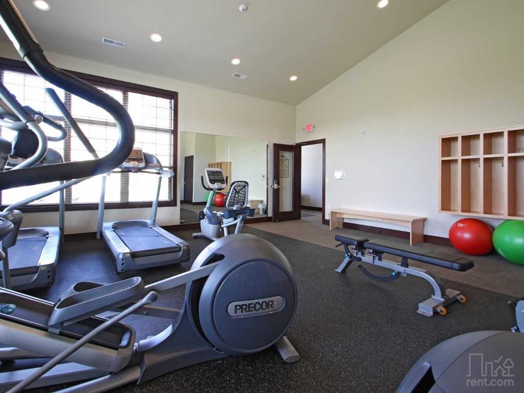a gym with cardio equipment and weights on the floor