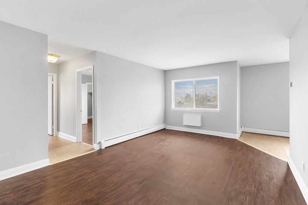 an empty living room with wood floors and white walls