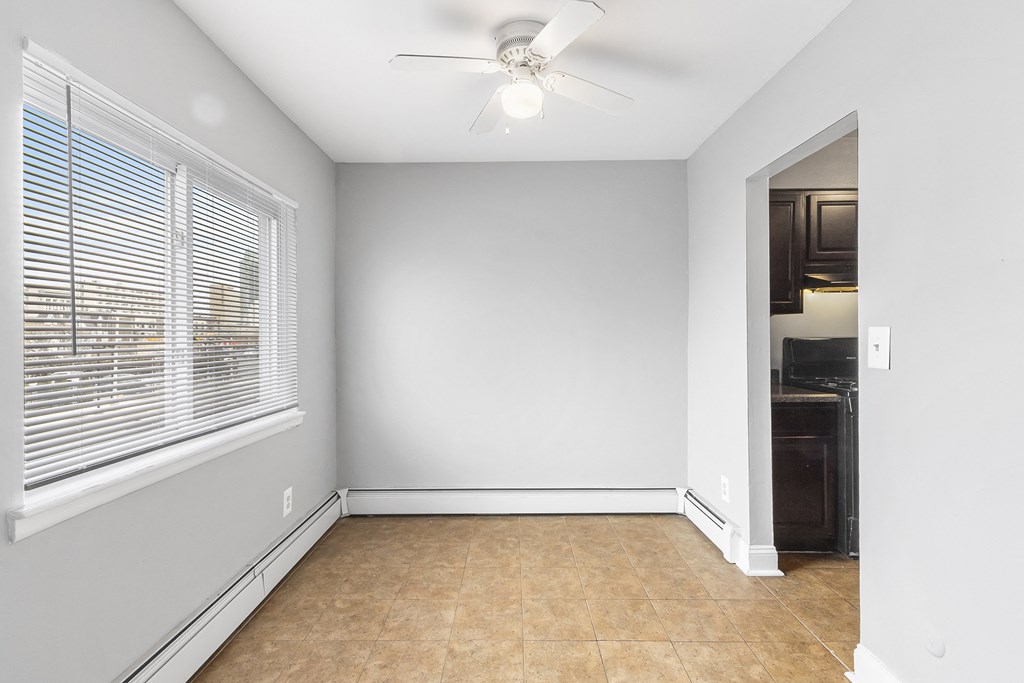 an empty room with a large window and a ceiling fan