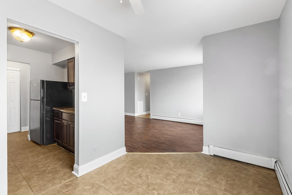 an empty living room with a kitchen and a door to a hallway