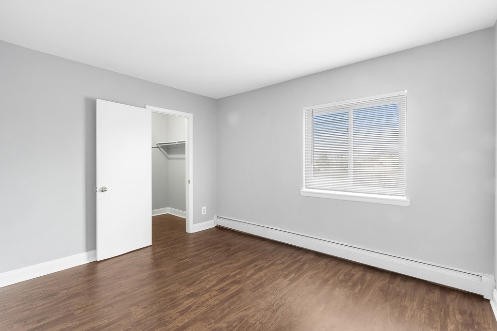 an empty room with wood floors and grey walls and a window