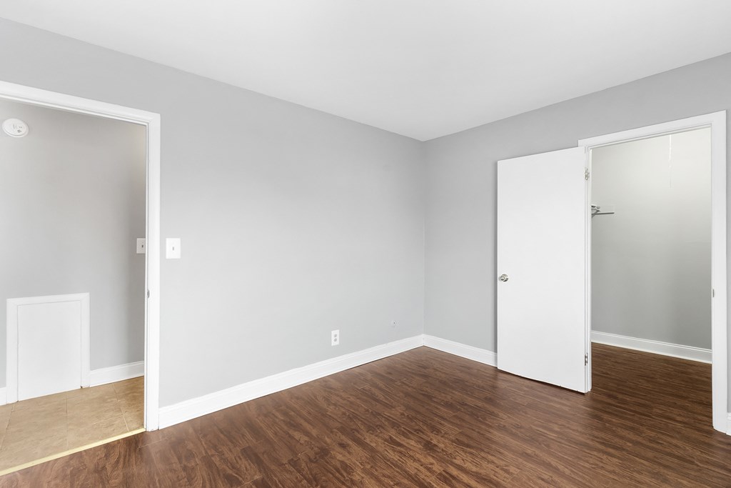 an empty room with wood floors and a door to a closet