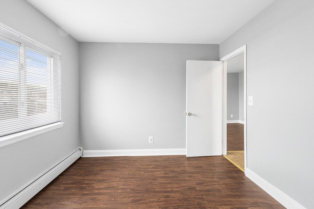 an empty room with wood flooring and a large window