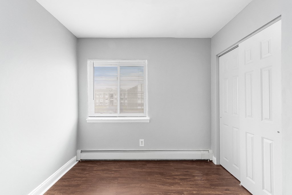 an empty room with wood floors and a window