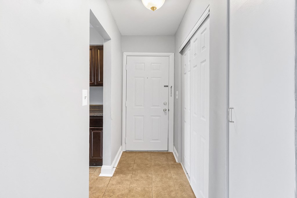 an empty hallway with a white door and a kitchen