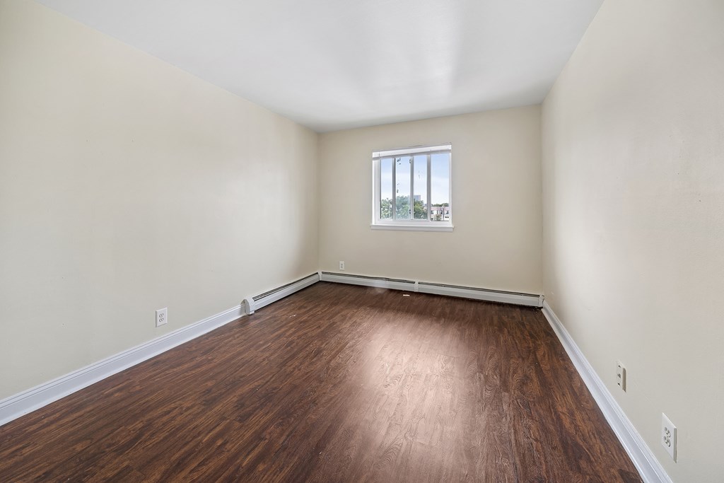 an empty living room with wood flooring and a window