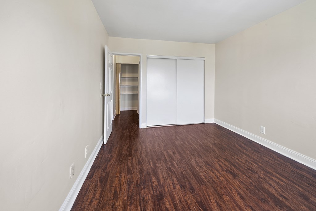 an empty living room with wood flooring and a closet