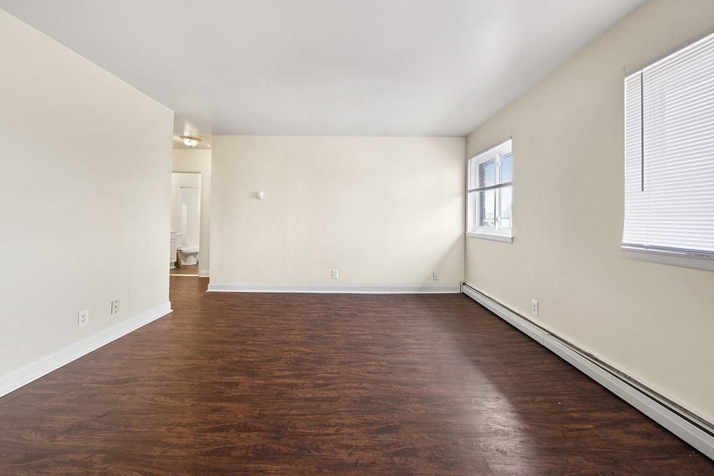 an empty living room with wood flooring and a window