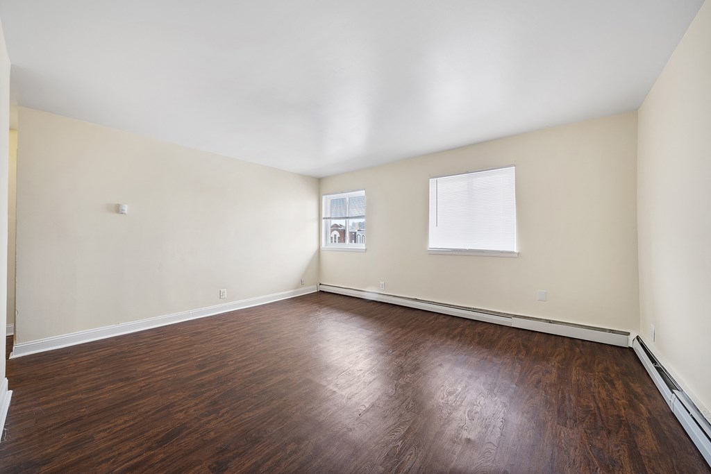 an empty living room with wood floors and white walls