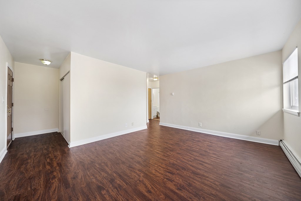 an empty living room with wood flooring and white walls