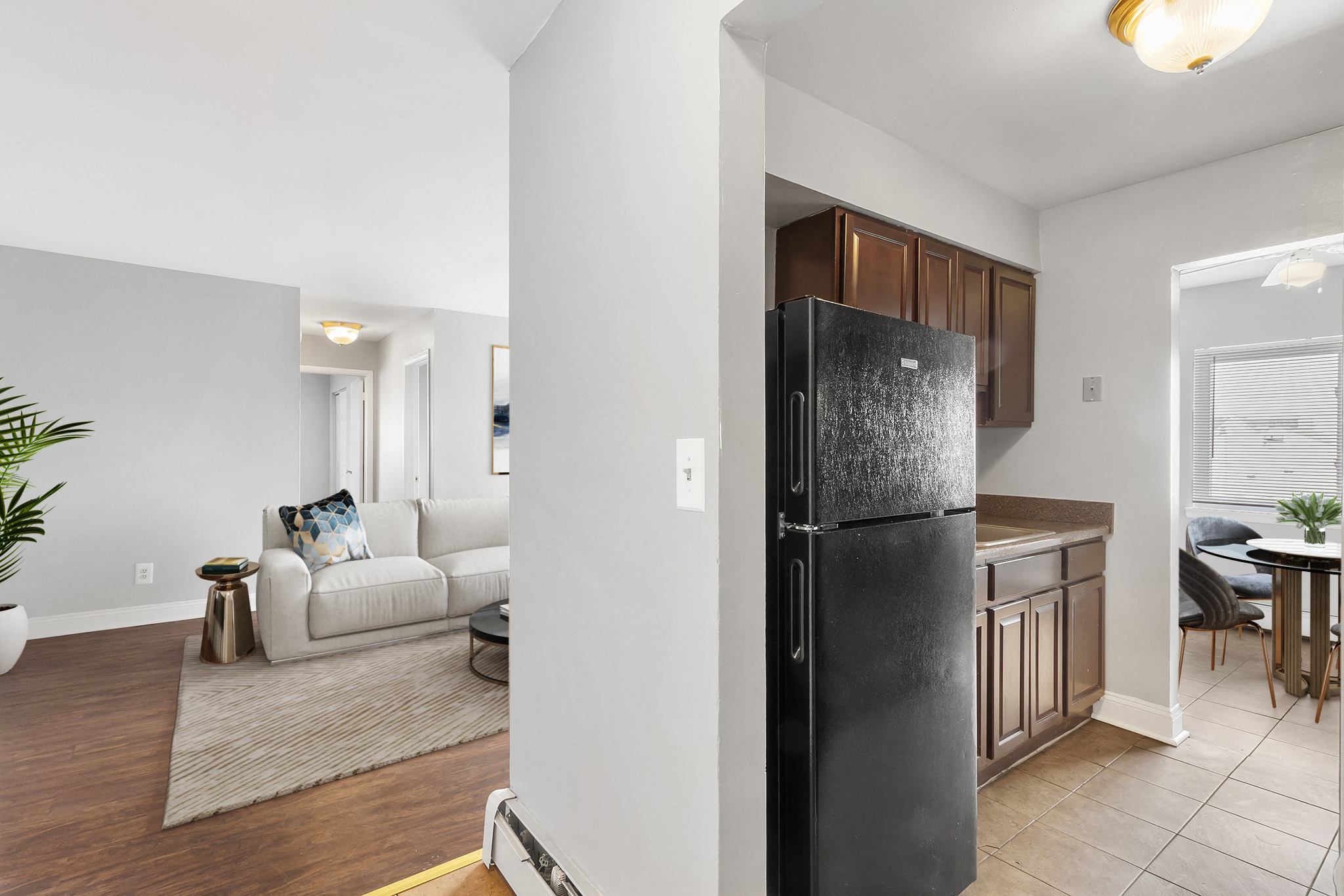 a kitchen with a refrigerator and a living room with a couch