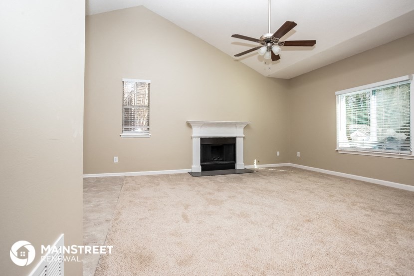 a living room with a fireplace and a ceiling fan