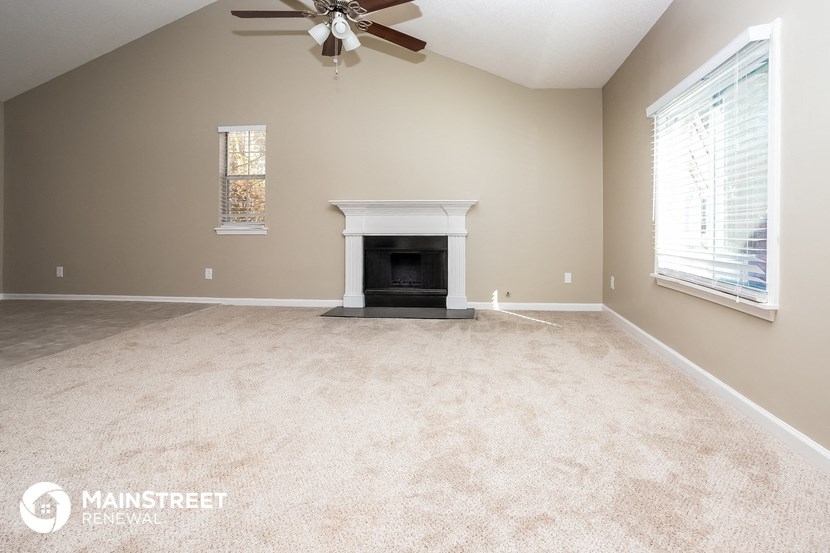 the living room has a fireplace and carpeted flooring and a ceiling fan