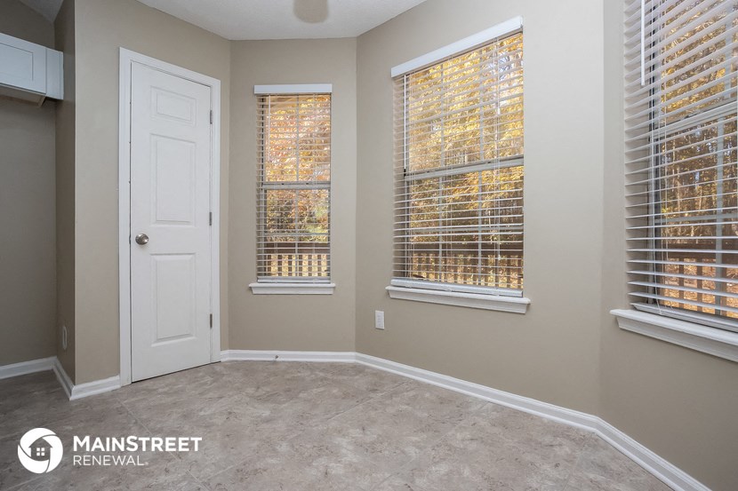 an empty room with three windows and a white door