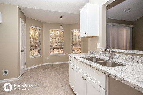 a kitchen with white cabinets and granite counter tops and a sink