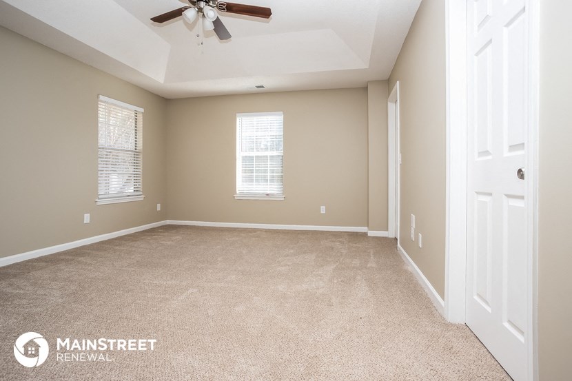 the master bedroom with carpeted flooring and a ceiling fan