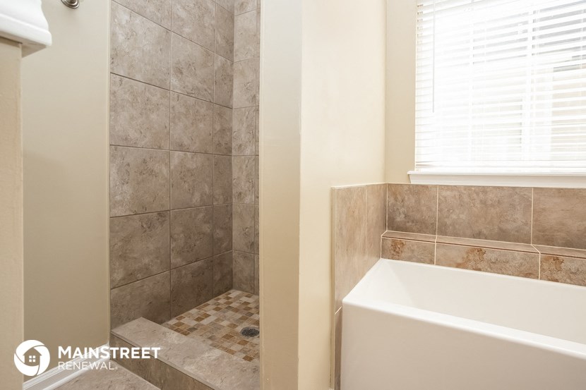a bathroom with a tub and a shower and a window