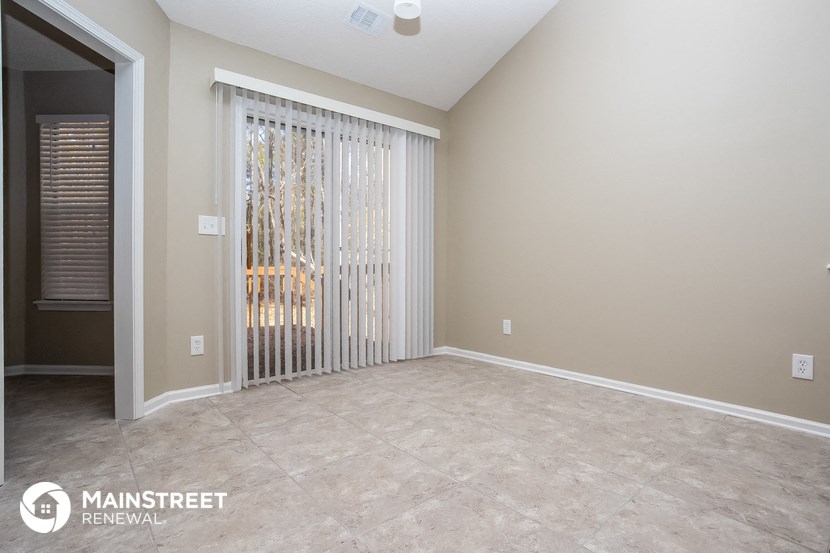 the living room of a house with a large patio door and a window