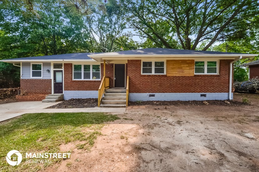 the front of a brick house with dirt and grass