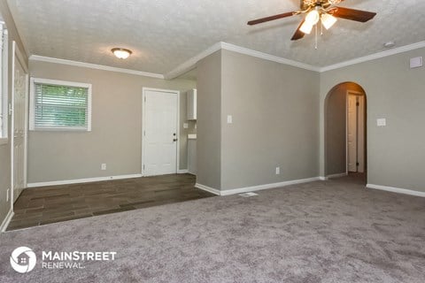 the living room of a home with carpet and a ceiling fan