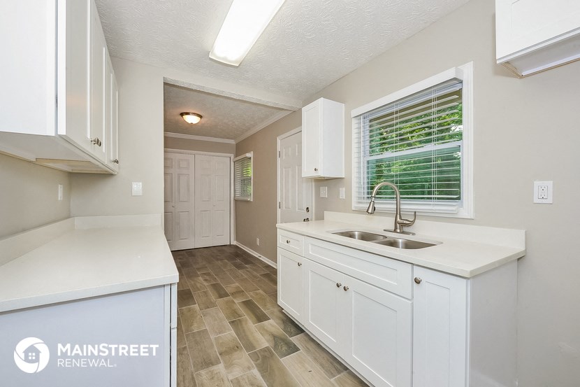a white kitchen with a sink and a window