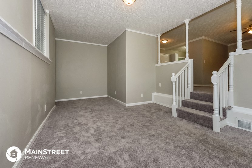 the upstairs living room and staircase of a house with carpeted stairs