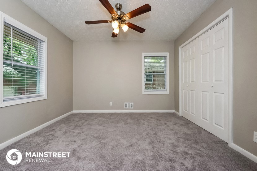 an empty room with a ceiling fan and a white door