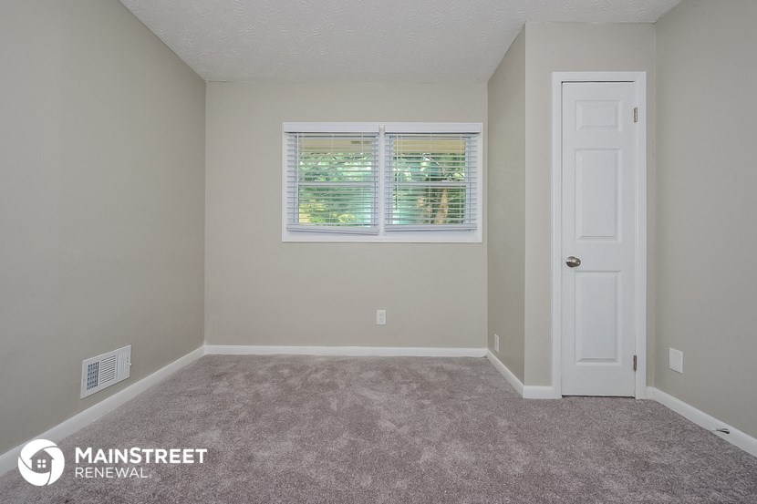 an empty room with a white door and a window