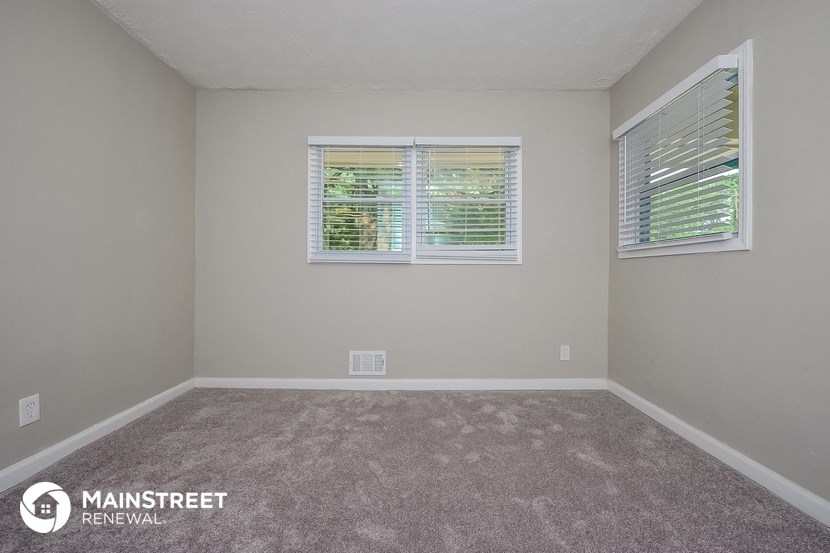 an empty room with two windows and a carpeted floor