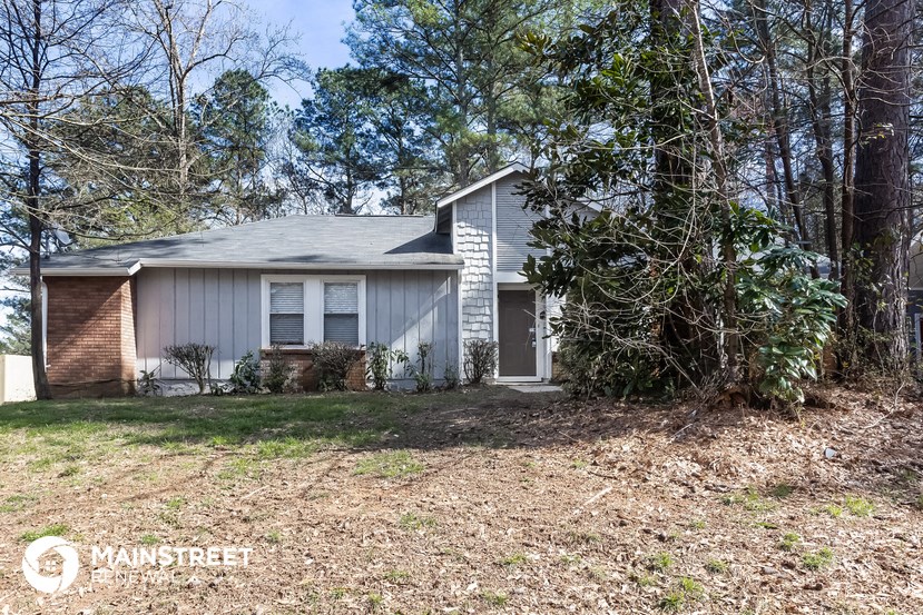 a small white house with a yard and trees
