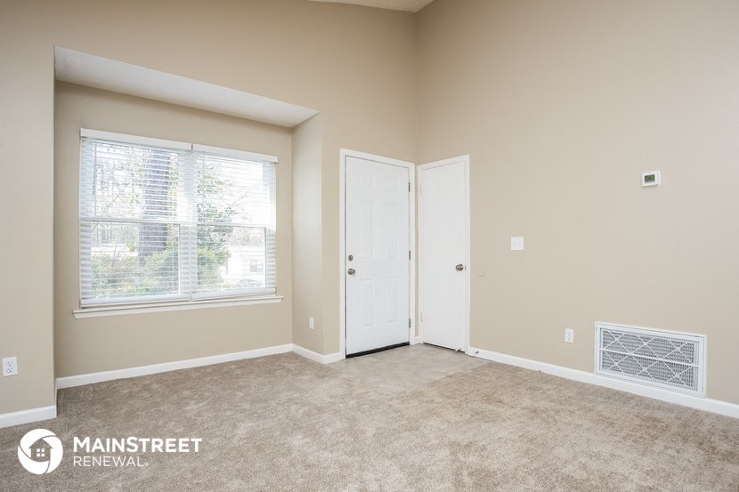 a bedroom with a door and a window and a carpeted floor